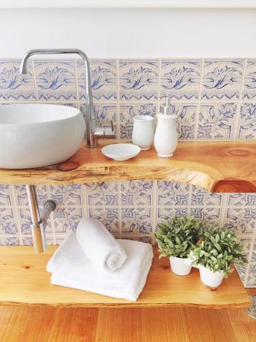 a bathroom with a sink and towels on a shelf at Quinta da Aranha in Arcos de Valdevez