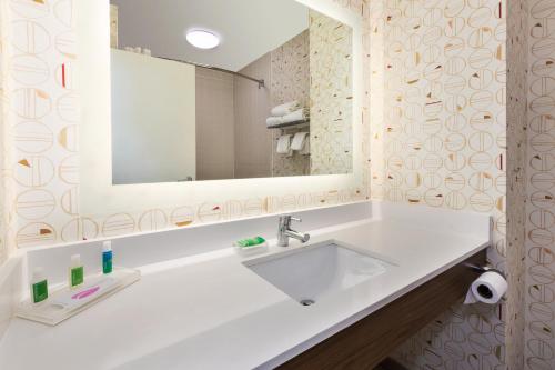 ein Badezimmer mit einem weißen Waschbecken und einem Spiegel in der Unterkunft Holiday Inn Grand Rapids - South, an IHG Hotel in Cutlerville