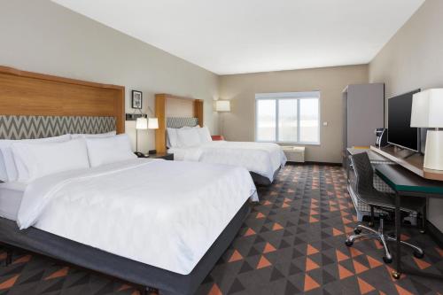 a hotel room with two beds and a desk at Holiday Inn & Suites Grand Rapids - South by IHG in Cutlerville