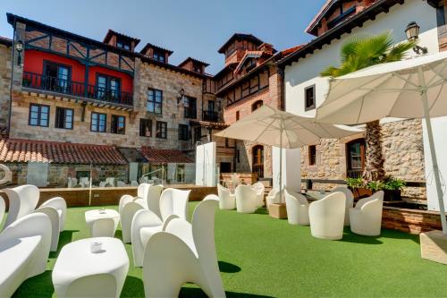 een rij witte stoelen en parasols op een patio bij Costa Esmeralda Suites in Suances