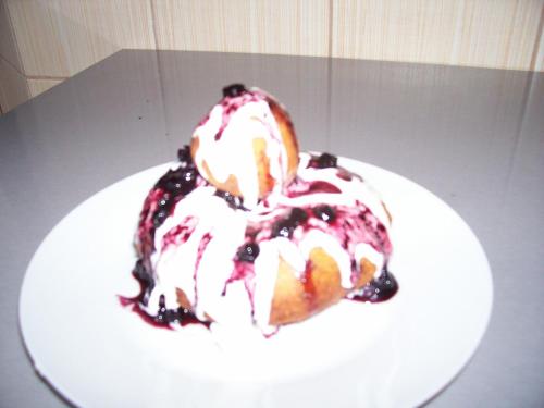 a bundt cake with blueberries and whipped cream on a plate at Pensiunea Mara in Deseşti