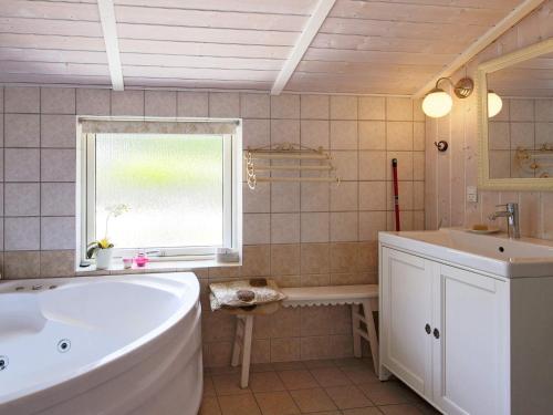 baño con bañera, lavabo y ventana en 4 person holiday home in F llenslev, en Føllenslev