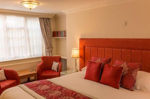 a hotel room with a bed and a red chair at Best Western Sysonby Knoll Hotel in Melton Mowbray