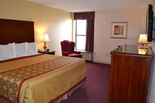a hotel room with a bed and a chair at Rodeway Inn High Point - Archdale in Archdale