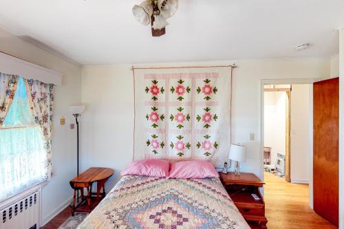 Classic Southold Country Charmer في سوثولد: غرفة نوم مع سرير مع نمط الزهور على الحائط