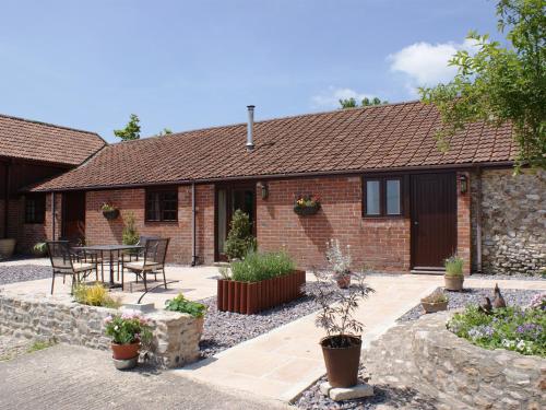 a cottage with a table and chairs in front of it at The Shippen in Northleigh