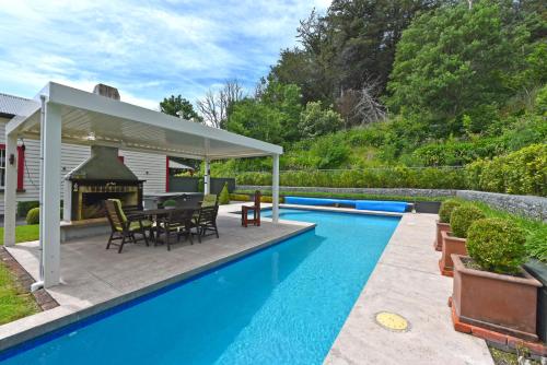 a patio with a table and a fireplace next to a swimming pool at India House & Ica Whare in Whareama, Nr Riversdale Beach in Whareama