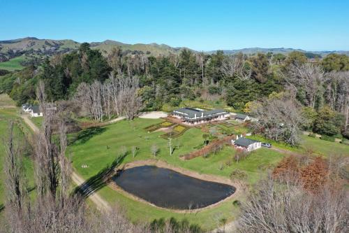 an aerial view of a house on a hill with a pond at India House & Ica Whare in Whareama, Nr Riversdale Beach in Whareama