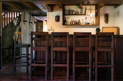 a bar with four wooden stools in a room at Mindo cozy house in Mindo