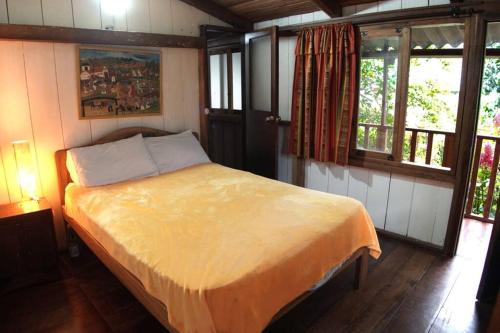 a bedroom with a bed in a room with windows at Mindo cozy house in Mindo