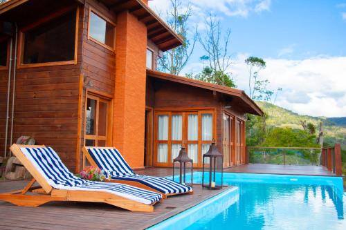 a house with two lounge chairs next to a swimming pool at Valle Ristretto in Gramado