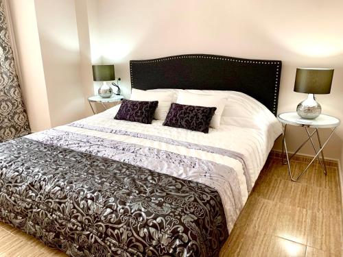 ein Schlafzimmer mit einem schwarzen und weißen Bett mit zwei Lampen in der Unterkunft Luxury Apartments Golden Beach Javea in Jávea