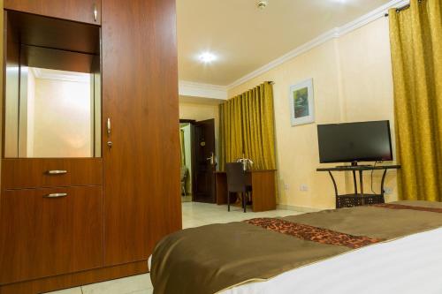 a hotel room with a bed and a television at Midindi Hotel in Accra