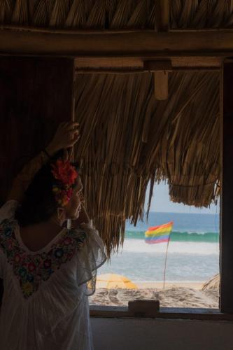 a woman standing in front of a window at the beach at La Máxima & LGBT in Zipolite