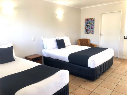 a hotel room with two beds and a table at Cottage Park Thermal Motel in Tauranga