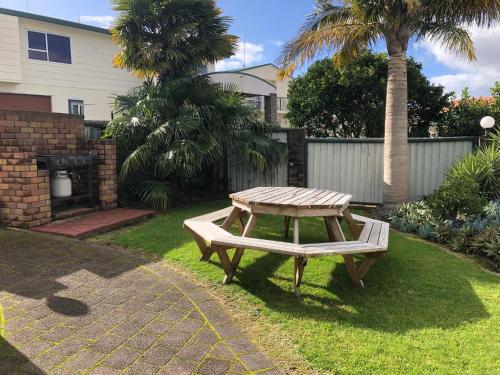 a picnic table in a yard with a palm tree at Cottage Park Thermal Motel in Tauranga