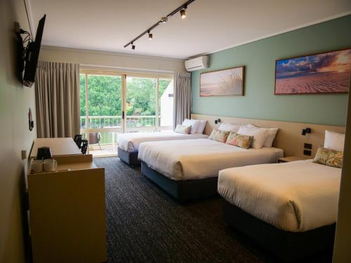 a hotel room with two beds and a window at Nightcap at Hinterland Hotel Nerang in Gold Coast
