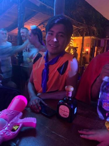 a man sitting at a table with a bottle of alcohol at La Máxima & LGBT in Zipolite