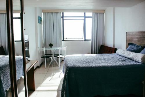 a bedroom with a bed and a table and a window at Flat 308 Vista Mar in Salvador