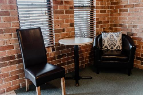 two chairs and a table in a room with a brick wall at Inverell Terrace Motor Lodge in Inverell