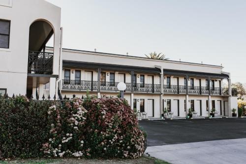 a white building with flowers in front of it at Inverell Terrace Motor Lodge in Inverell