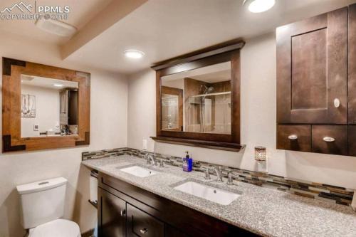 a bathroom with two sinks and a toilet and a mirror at 2 Master Suites/3 King Beds/4 Bath/Mins to Airport in Colorado Springs