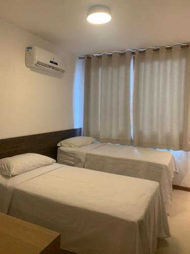 Cette chambre comprend 2 lits et une fenêtre. dans l'établissement Maraú Beach House Flat 107 pé na areia - Cond Dreamland Apart Taipú de Fora Barra Grande-BA, à Barra Grande