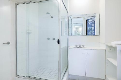 a white bathroom with a shower and a sink at The Breakers in Gold Coast