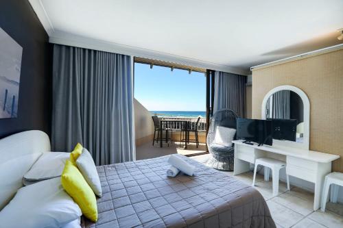 a hotel room with a bed and a desk and a television at The Breakers in Gold Coast