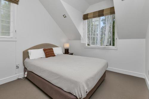 une chambre blanche avec un lit et deux fenêtres dans l'établissement Russell Cottages - Russell Holiday Home, à Russell