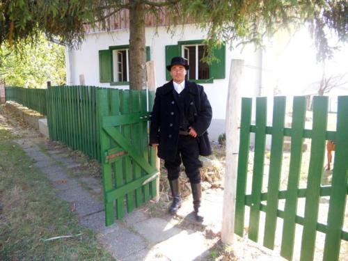 a man standing next to a green fence at Erdősmecskei sváb vendégházak és Jurtaszállás in Erdősmecske
