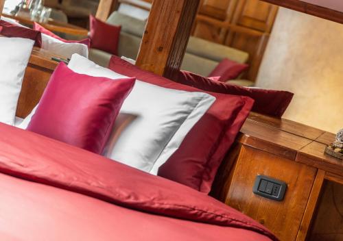 a pile of red and white pillows on a bed at Garden Wellness Hotel S in Andalo