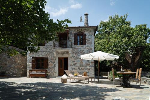 kamienny budynek z parasolem i stołem w obiekcie Helene Eco Luxury Villa w mieście Tsagarada