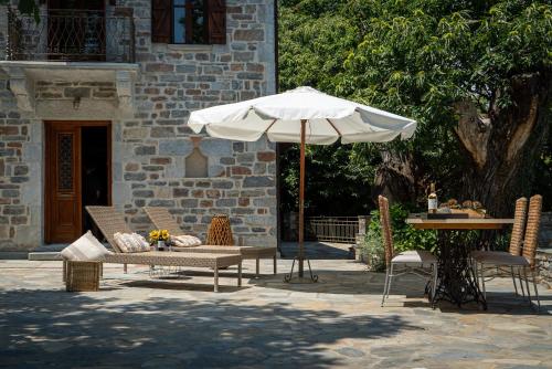 a patio with a table and an umbrella at Helene Eco Luxury Villa in Tsagarada