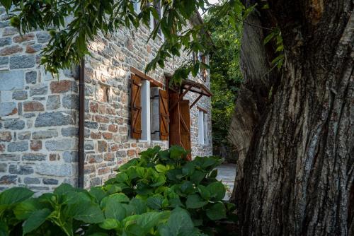 a brick building with a window and a tree at Helene Eco Luxury Villa in Tsagarada