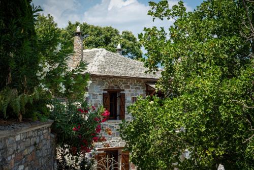 kamienny dom otoczony drzewami i kwiatami w obiekcie Helene Eco Luxury Villa w mieście Tsagarada
