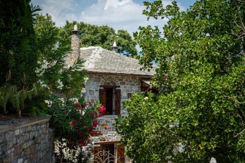 a stone house surrounded by trees and flowers at Helene Eco Luxury Villa in Tsagarada