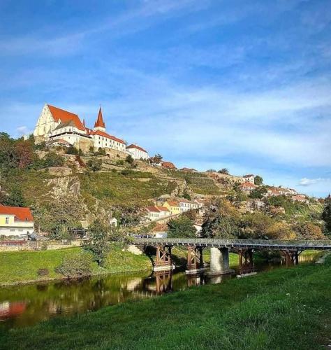 a bridge over a river with a castle on a hill at Apartmán pod hradem in Znojmo