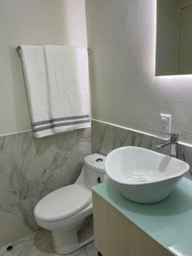 y baño con aseo blanco y lavamanos. en Constanza Lofts Executives en Zapopan Jalisco, en Guadalajara