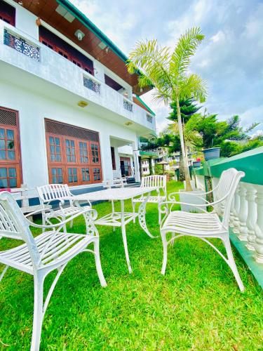 a group of white chairs and tables in front of a house at Srilak View Holiday Inn in Haputale