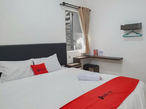 a bedroom with a white bed with a red blanket at RedDoorz near Istana Plaza 3 in Bandung