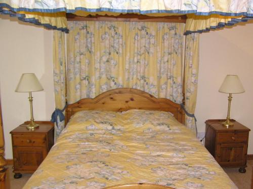 a bedroom with a bed with a canopy and two lamps at The Antlers in Lybster