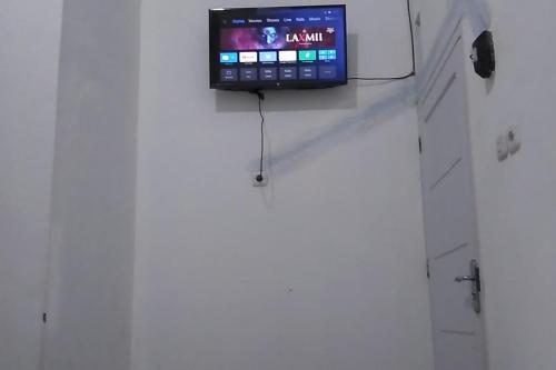 a television on a white wall in a room at Guesthouse Berlian Batang Syariah near Kampung Kalisalak Park in Pekalongan