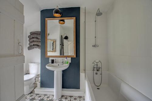 een badkamer met een wastafel, een spiegel en een bad bij Sweet & cosy 10 Bridewell Cottage with parking available upon request in Bury Saint Edmunds