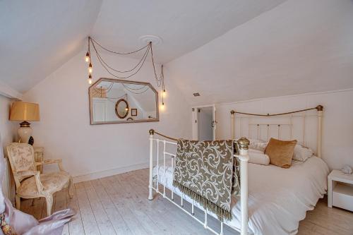 een slaapkamer met een wit bed en een stoel bij Sweet & cosy 10 Bridewell Cottage with parking available upon request in Bury Saint Edmunds