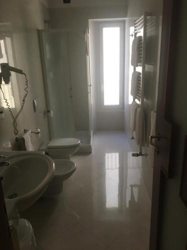 a bathroom with two sinks and a toilet and a window at Hotel San Marco in Prato