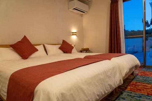 a hotel room with a large bed with a window at 美ら海ビレッジ プール＆テラス in Motobu