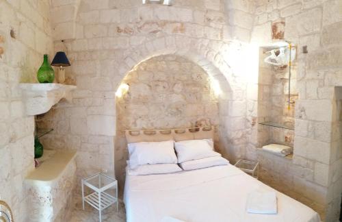 a bedroom with a white bed and a stone wall at Il Casolare nel relax in Ostuni