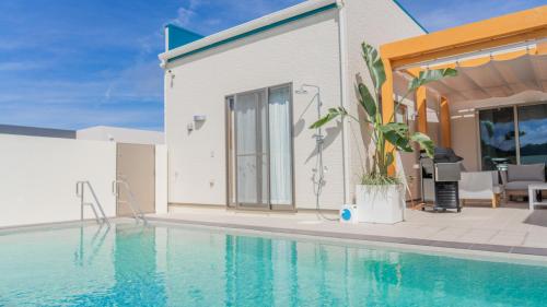 a swimming pool in front of a house at 美ら海ビレッジ プール＆テラス in Motobu