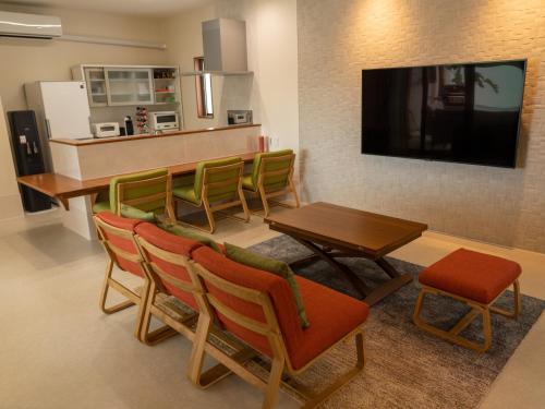 a living room with a table and chairs and a television at 美ら海ビレッジ プール＆テラス in Motobu